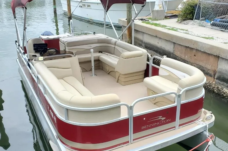 Slide: The Image of 2012 Bennington 22 SSI boat interior with beige seating by a dock. - 6