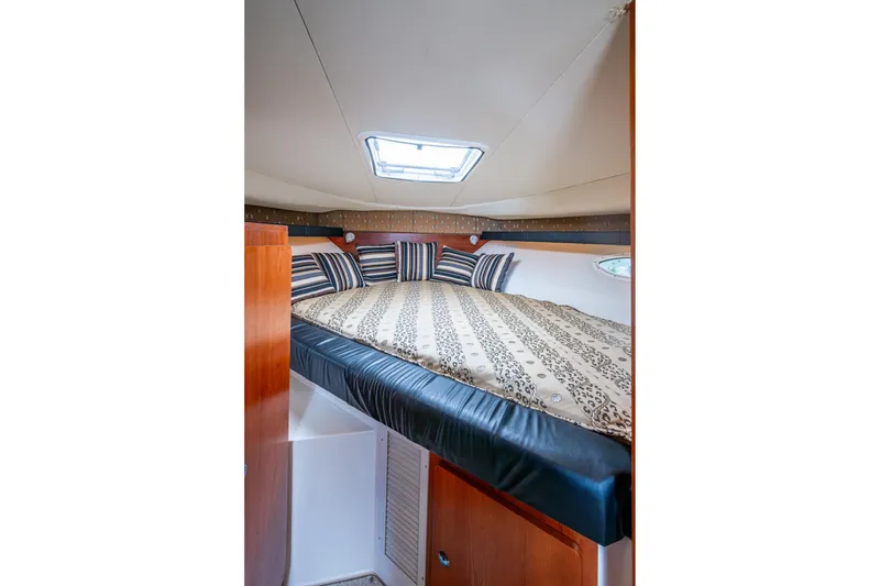 Slide: The Image of Interior cabin of 2002 Sport-Craft 3150 Sportfish with bed and striped pillows. - 13