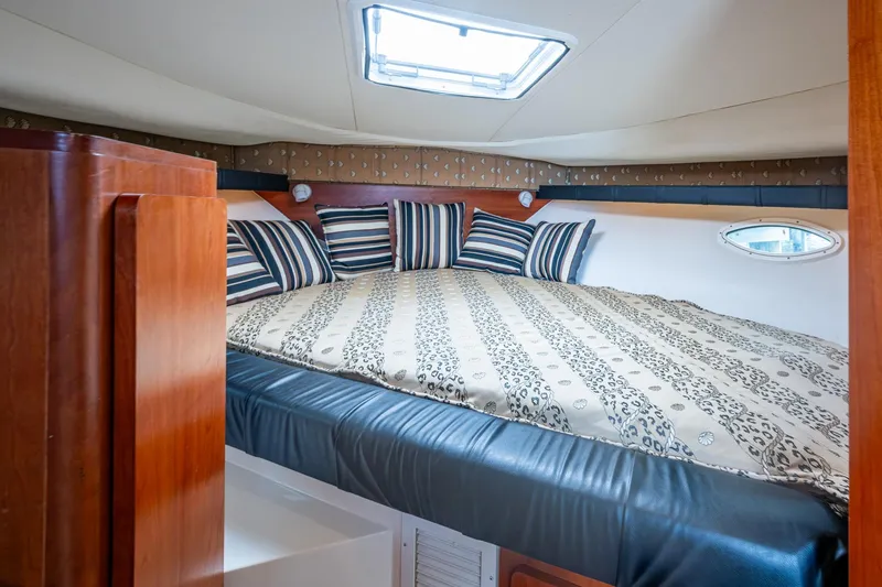 Slide: The Image of Luxurious cabin interior of 2002 Sport-Craft 3150 Sportfish with striped pillows and patterned bedding. - 14