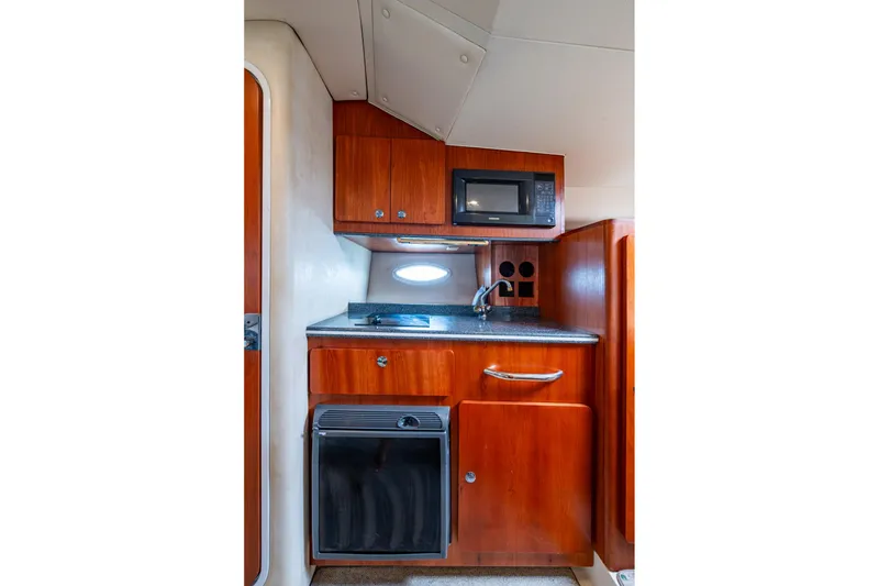 Slide: The Image of 2002 Sport-Craft 3150 Sportfish interior kitchen with wood cabinets, microwave, and sink. - 15