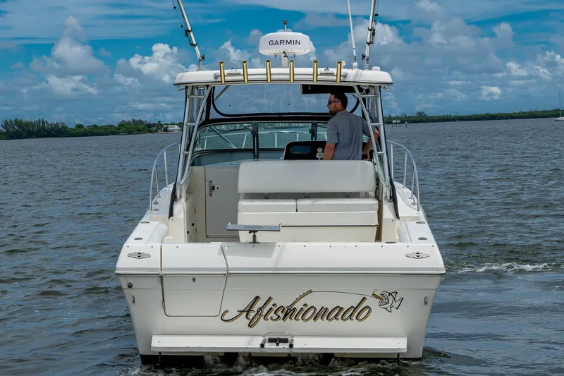 Slide: The Image of 2002 Sport-Craft 3150 Sportfish boat on water, rear view with "Aficionado" name. - 6