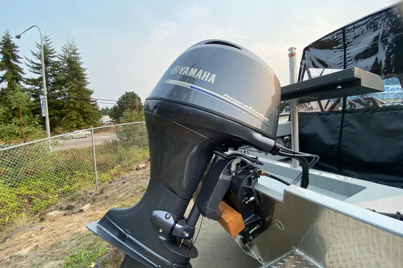 Slide: The Image of 2026 Hewescraft 180 Sportsman with Yamaha outboard motor, parked near a chain-link fence. - 5