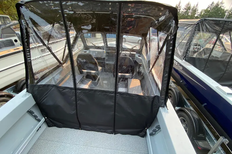 Slide: The Image of 2026 Hewescraft 180 Sportsman boat interior with protective cover, parked outdoors. - 7