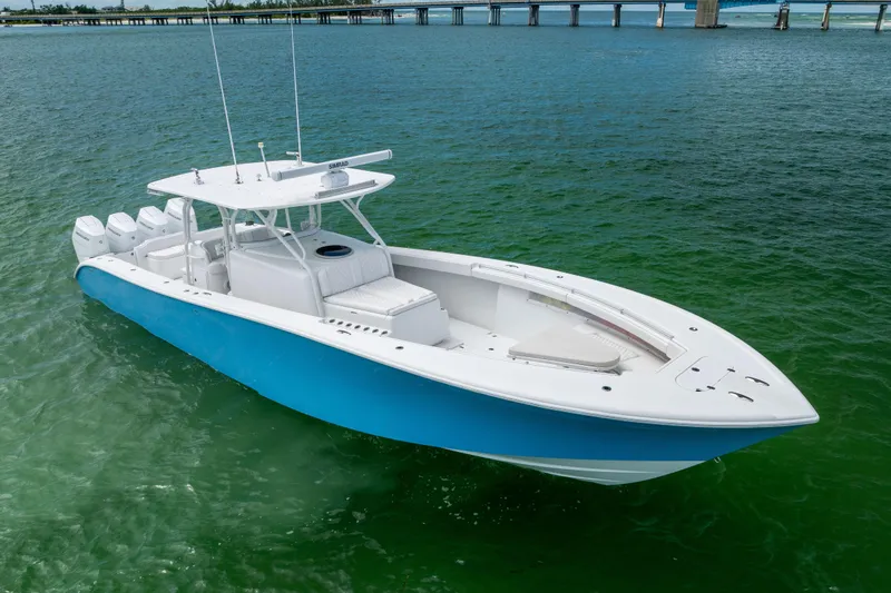 Slide: The Image of 2009 Yellowfin 42 Offshore boat on clear green water, featuring a sleek blue and white design. - 3