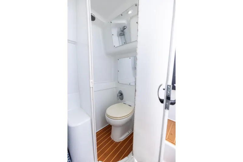 Slide: The Image of 2009 Yellowfin 42 Offshore boat bathroom with toilet and shower, featuring wood-style flooring. - 51