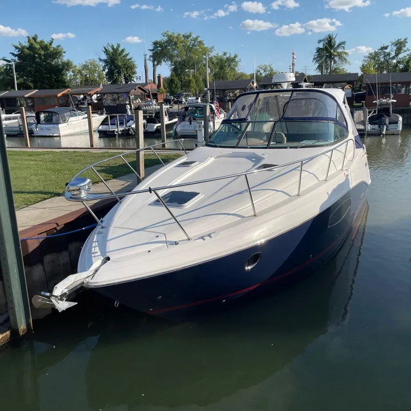 The Image of 2019 Rinker 370 EX boat docked in a marina, surrounded by other vessels. - 0