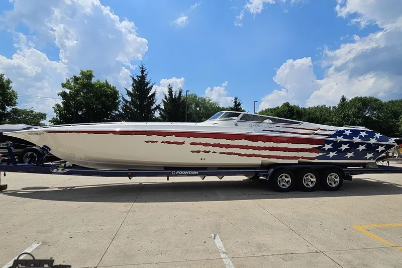 Slide: The Image of 2007 Fountain 42 Lightning boat with American flag design on trailer under blue sky. - 15