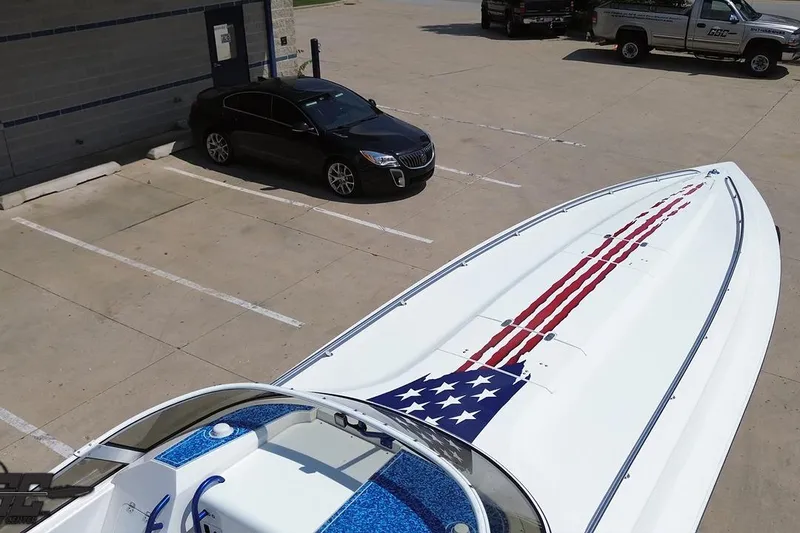 Slide: The Image of 2007 Fountain 42 Lightning boat with American flag design, parked near vehicles. - 64