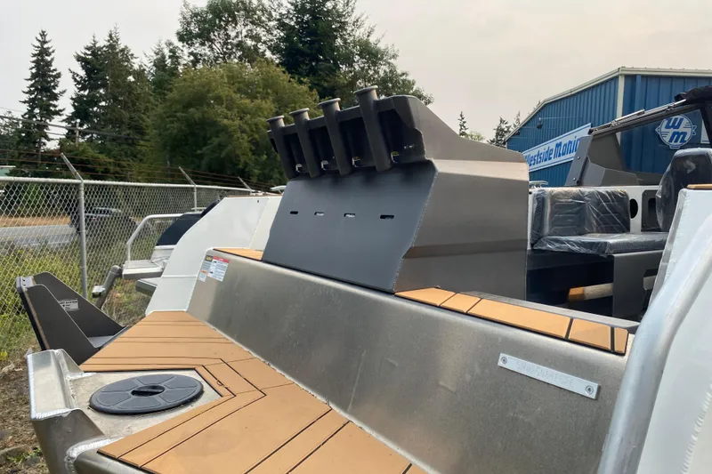 Slide: The Image of 2026 Stabicraft 2050 Trekker boat with rod holders, docked near a blue building. - 3