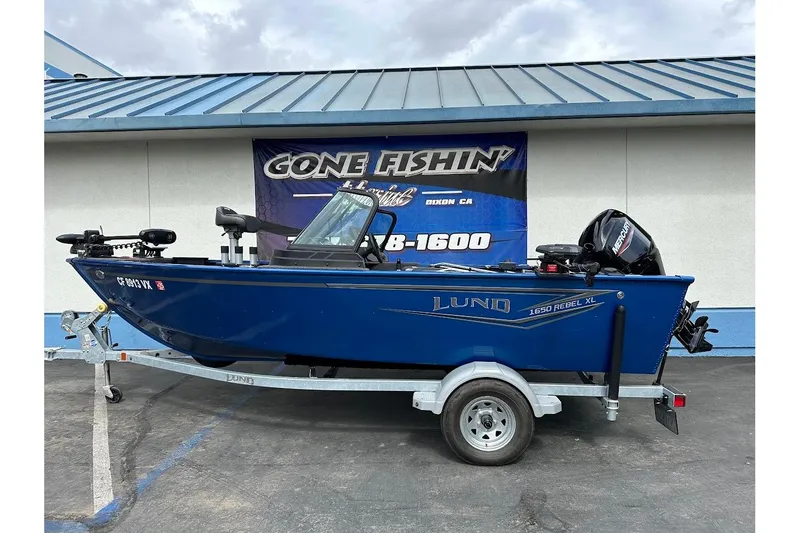 Slide: The Image of 2024 Lund 1650 Rebel XL Sport boat on trailer, displayed at dealership. - 1