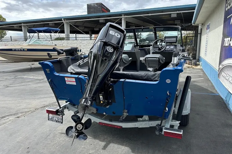 Slide: The Image of 2024 Lund 1650 Rebel XL Sport boat with outboard motor, parked on trailer. - 10