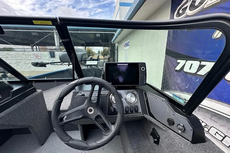Slide: The Image of 2024 Lund 1650 Rebel XL Sport boat dashboard with steering wheel and navigation display. - 20