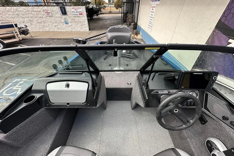 Slide: The Image of 2024 Lund 1650 Rebel XL Sport boat interior with steering wheel and dashboard controls. - 22