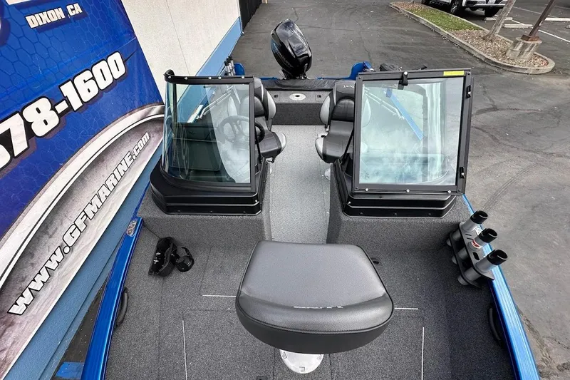 Slide: The Image of 2024 Lund 1650 Rebel XL Sport boat interior with seating and windshield, parked outdoors. - 28