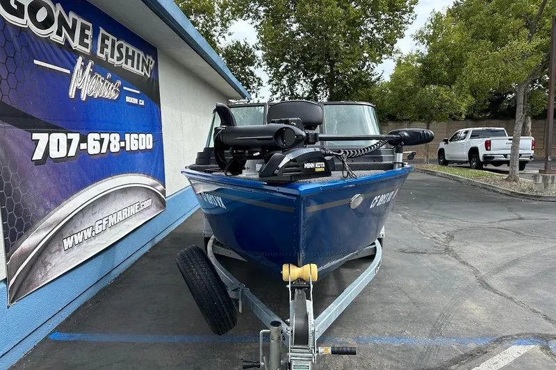 Slide: The Image of 2024 Lund 1650 Rebel XL Sport boat on trailer outside marine shop. - 3