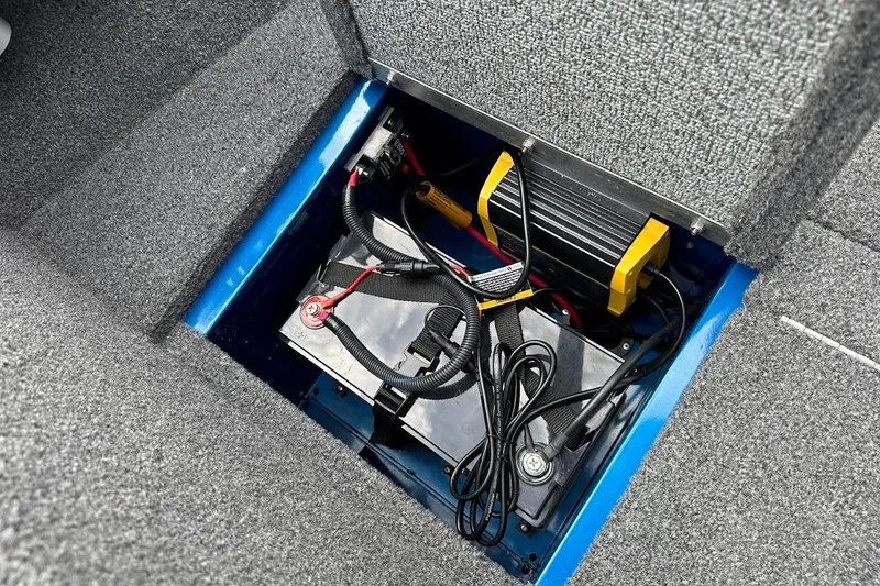 Slide: The Image of 2024 Lund 1650 Rebel XL Sport battery compartment with wiring and charger. - 31