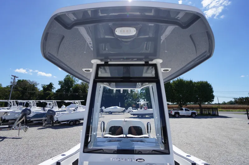 Slide: The Image of 2026 Tidewater 220 CC Adventure boat with T-top, parked outdoors under blue sky. - 16