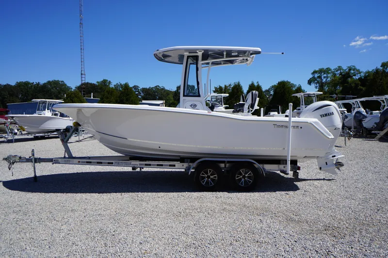 Slide: The Image of 2026 Tidewater 220 CC Adventure boat on trailer, side view, clear sky background. - 57