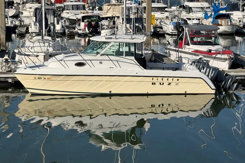 Slide: The Image of 2005 Glacier Bay 2680 Coastal Runner boat docked in a marina, reflecting on water. - 0