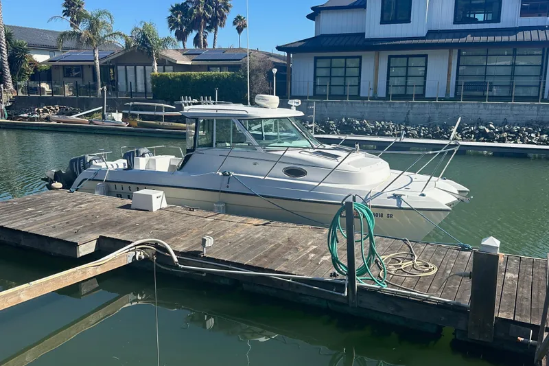Slide: The Image of 2005 Glacier Bay 2680 Coastal Runner docked in a marina, surrounded by waterfront homes. - 1