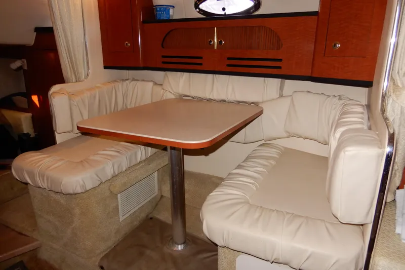 Slide: The Image of 2004 Sea Ray 280 Sundancer cabin interior with cozy dining area and cushioned seating. - 26