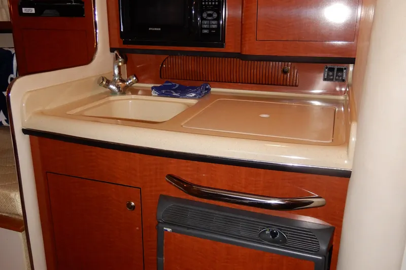 Slide: The Image of 2004 Sea Ray 280 Sundancer galley with sink, microwave, and storage cabinets. - 27