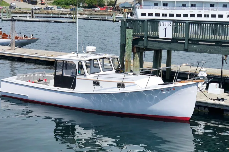 The Image of White 2015 Holland 32 boat docked at Pier 1, reflecting on calm water. - 0