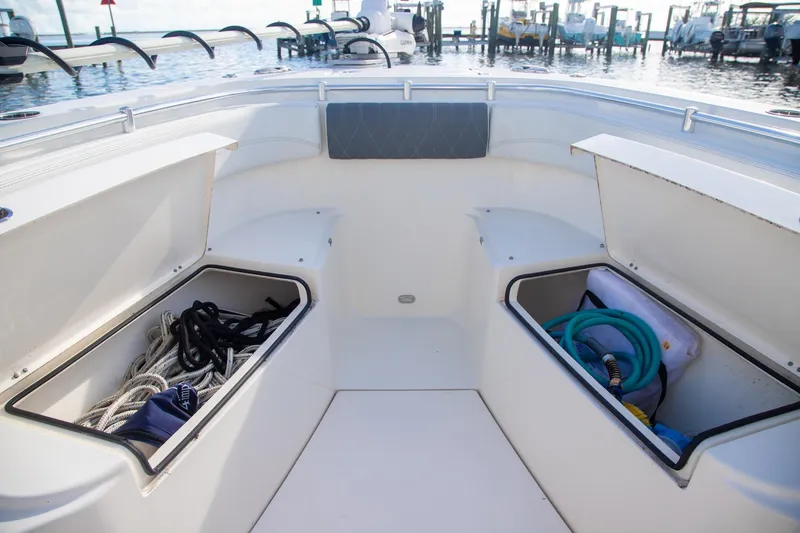 Slide: The Image of 2023 Cobia 280 Center Console boat storage compartments with ropes and hose, docked at marina. - 14