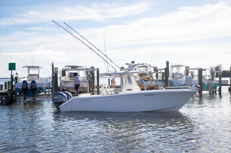 Slide: The Image of 2023 Cobia 280 Center Console boat docked at a marina with other vessels. - 18
