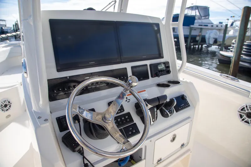 Slide: The Image of 2023 Cobia 280 Center Console boat dashboard with steering wheel and navigation screens. - 4
