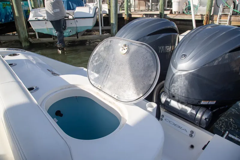 Slide: The Image of 2023 Cobia 280 Center Console boat with open hatch and dual Yamaha engines. - 9