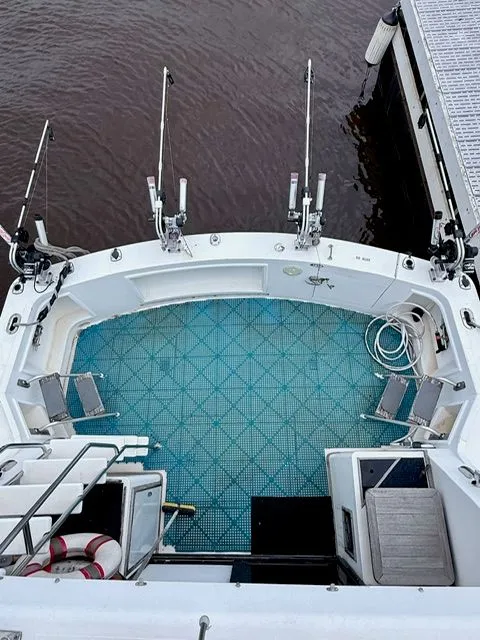 Slide: The Image of Fishing boat deck with rod holders and blue patterned flooring, docked at a marina. - 3