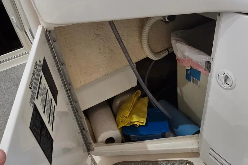 Slide: The Image of Storage compartment of a 1998 Sea Ray 280 Sun Sport boat with cleaning supplies. - 13
