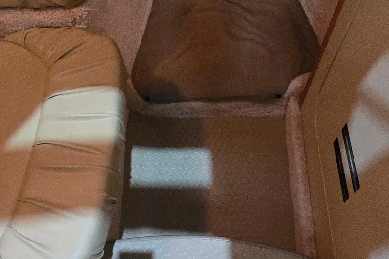 Slide: The Image of Interior of a 1998 Sea Ray 280 Sun Sport boat, featuring beige seating and carpeted flooring. - 23