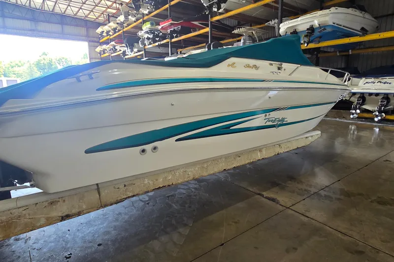 Slide: The Image of 1998 Sea Ray 280 Sun Sport boat in storage, featuring teal and white design. - 5