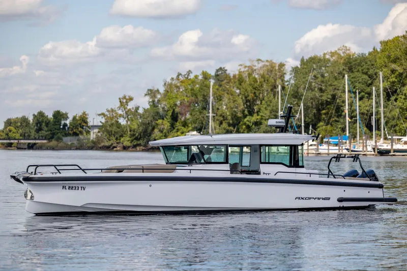 Slide: The Image of 2024 Axopar 37 XC boat on calm water with trees and clouds in the background. - 34