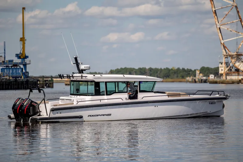 Slide: The Image of 2024 Axopar 37 XC boat on calm water near industrial dock. - 39