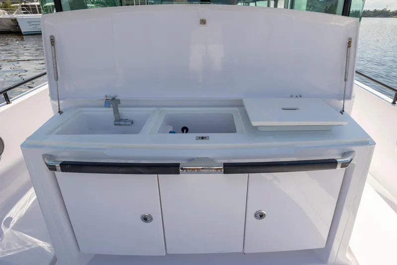 Slide: The Image of 2024 Axopar 37 XC boat kitchenette with sink and storage, docked by the water. - 44