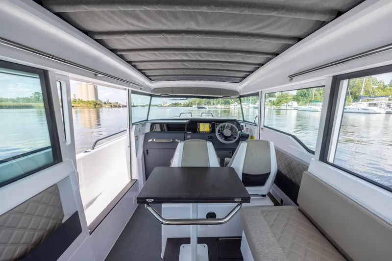 Slide: The Image of 2024 Axopar 37 XC interior with modern helm, seating, and panoramic windows on the water. - 54