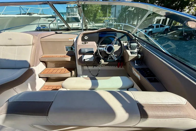 Slide: The Image of 2017 Regal 32 Express boat interior with seating, sink, and steering wheel, docked by a river. - 13