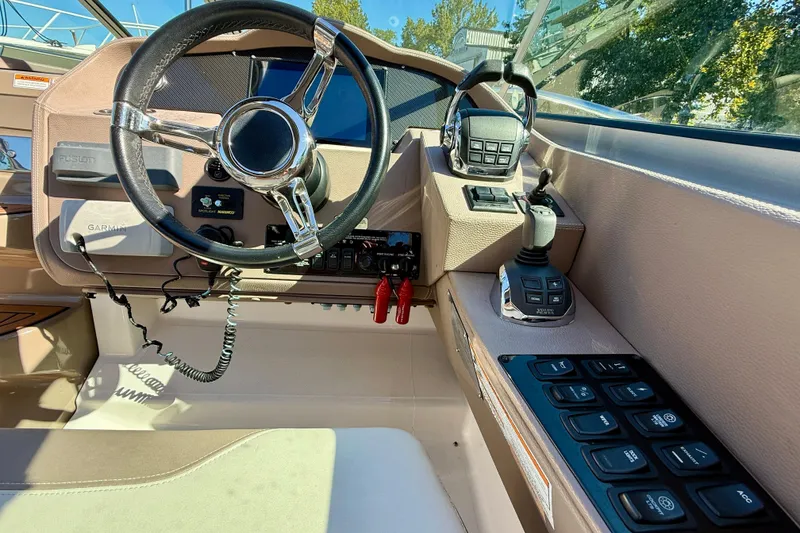 Slide: The Image of 2017 Regal 32 Express boat interior with helm, seating, and kitchenette on a sunny day. - 15