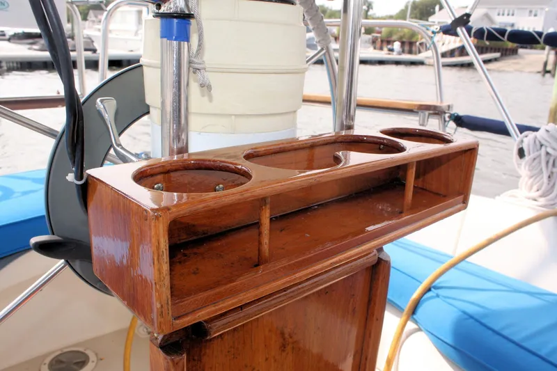 Slide: The Image of Wooden cup holder on 1988 Pearson 31 sailboat cockpit, featuring blue seating and steering wheel. - 14