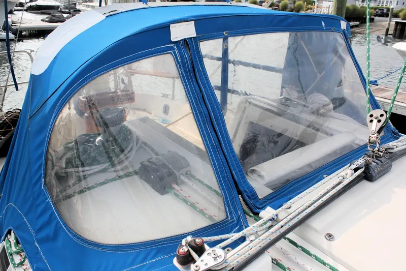 Slide: The Image of 1988 Pearson 31 sailboat cockpit with blue canvas cover and clear windows. - 16