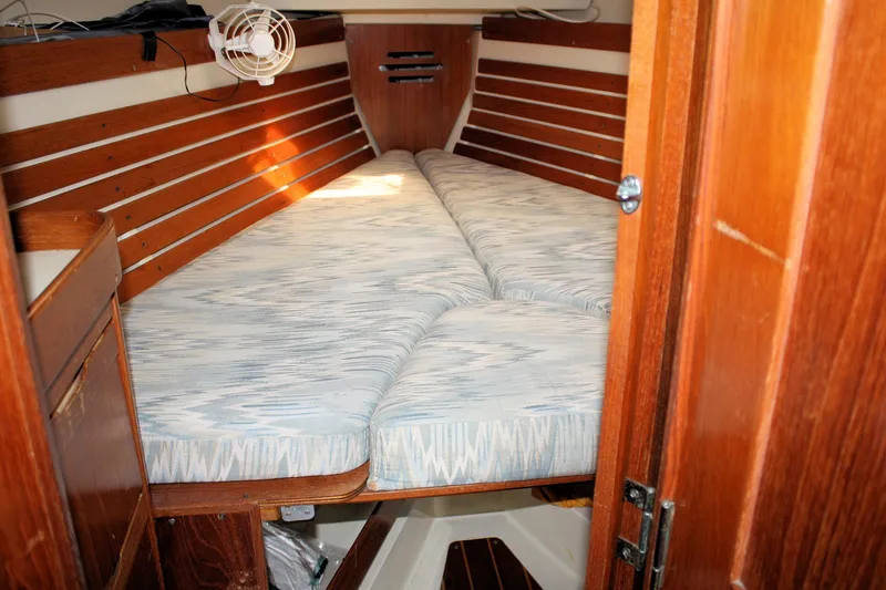 Slide: The Image of Cozy cabin interior of 1988 Pearson 31 sailboat with wooden paneling and cushioned berth. - 24