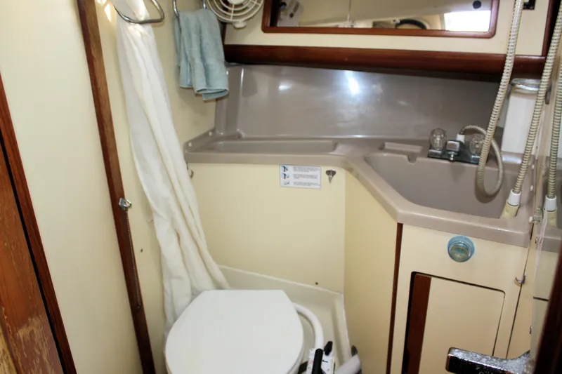 Slide: The Image of 1988 Pearson 31 sailboat bathroom with sink, toilet, and shower curtain. - 28