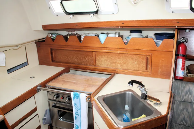 Slide: The Image of 1988 Pearson 31 sailboat galley with stove, sink, and wooden cabinetry. - 38