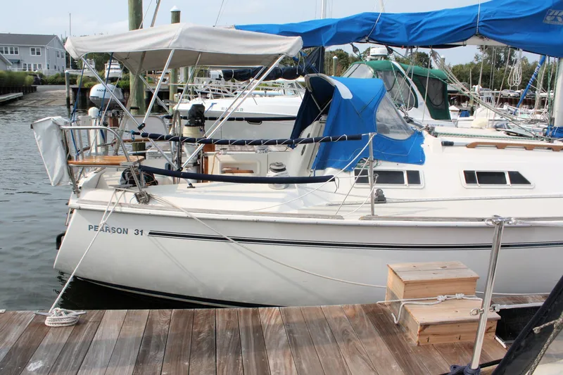 Slide: The Image of 1988 Pearson 31 sailboat docked at marina with blue and white covers. - 4
