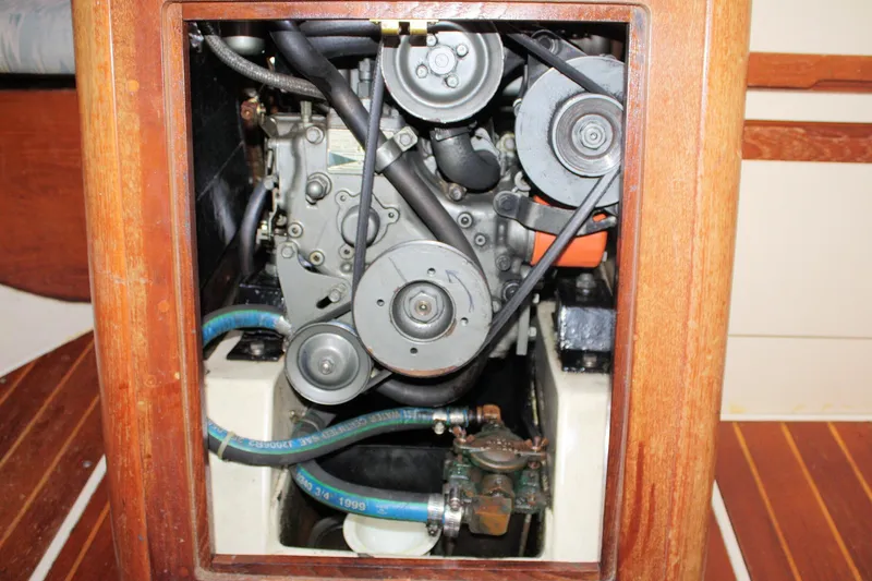 Slide: The Image of Engine compartment of a 1988 Pearson 31 sailboat, showcasing mechanical components and wooden paneling. - 54