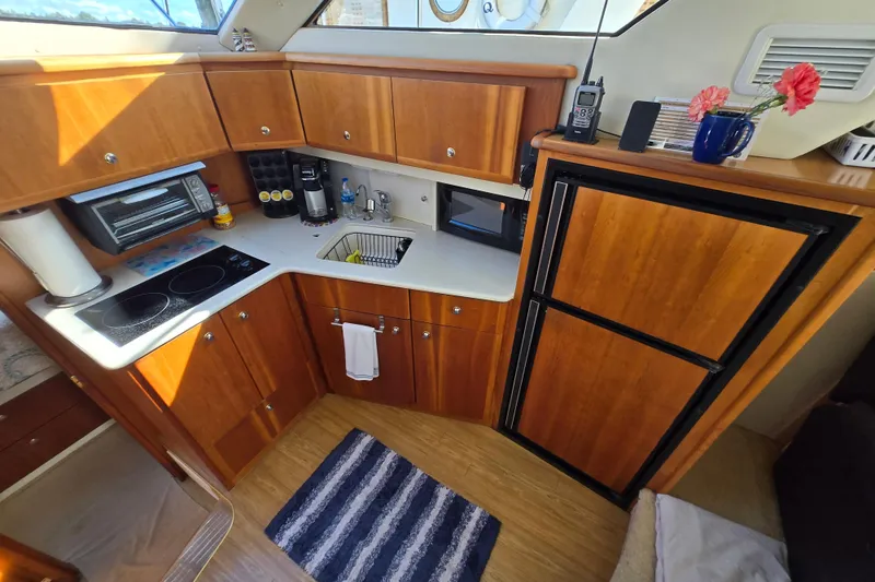 Slide: The Image of 2002 Silverton 351 Sedan Cruiser kitchen with wooden cabinets, appliances, and striped rug. - 4