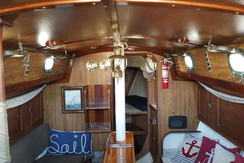 Slide: The Image of Interior of 1977 Custom Bodega 30 sailboat with wooden decor and nautical-themed cushions. - 13